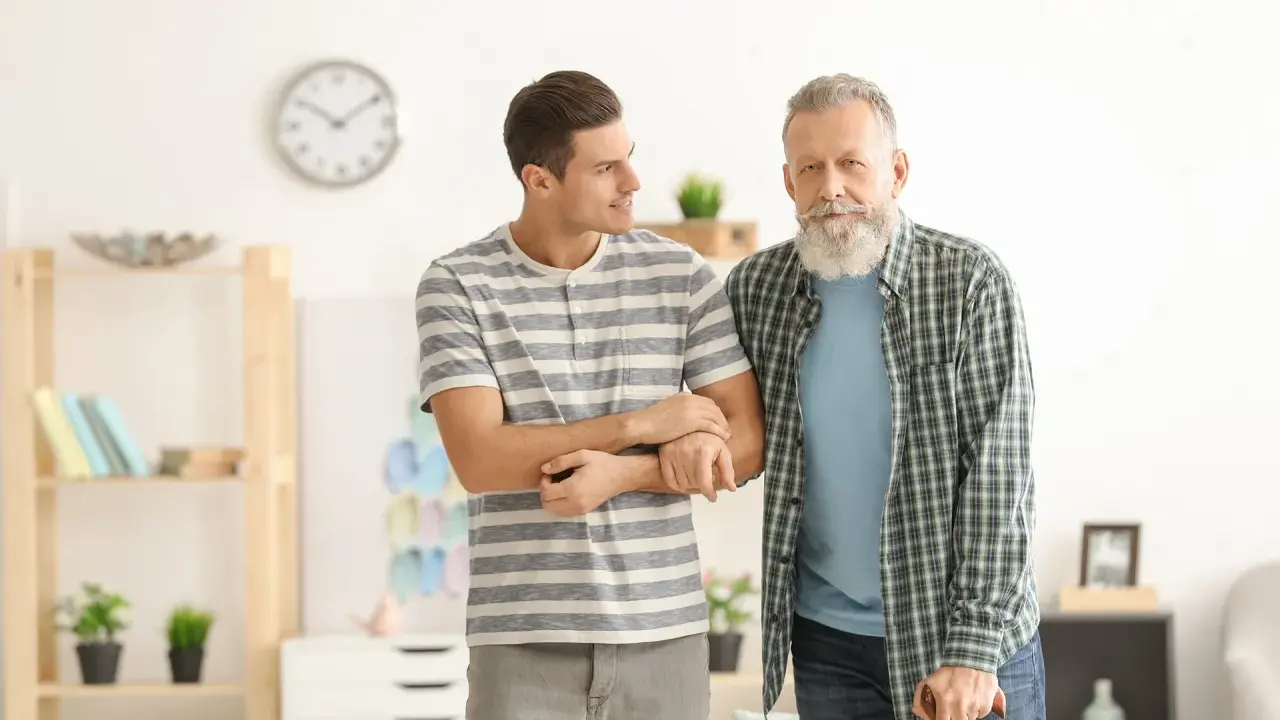 Giovane uomo supporta un anziano con bastone, entrambi con espressione speranzosa per un'aspettativa lavoro tempo indeterminato.