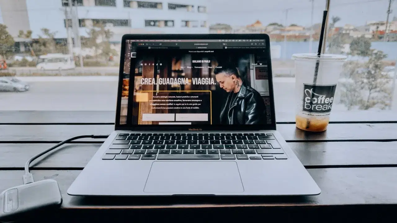 Un laptop aperto su un sito web che spiega cosa fa un content creator, con una bevanda accanto.