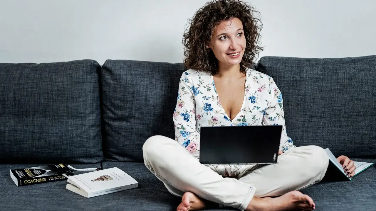 Donna con laptop e libri sul divano, esplora quali lavori si possono fare da casa.