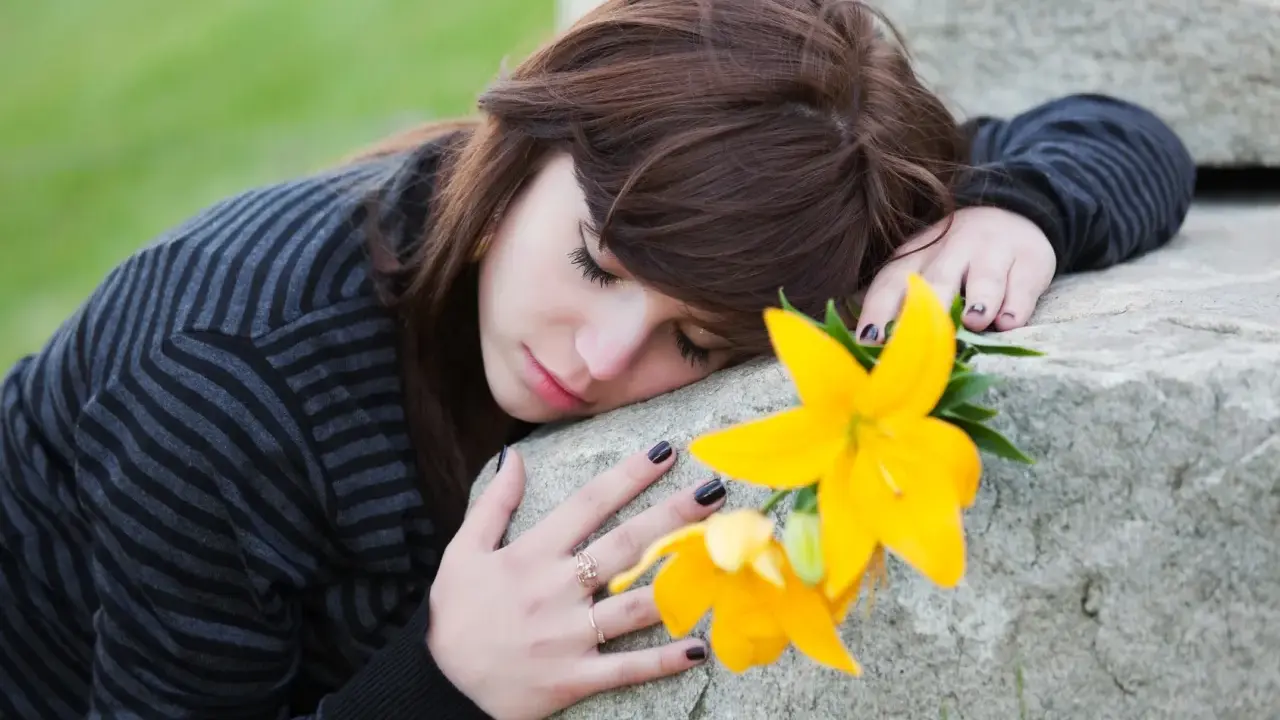 Ragazza con fiore giallo, triste, forse in attesa di un permesso per lutto suocero.