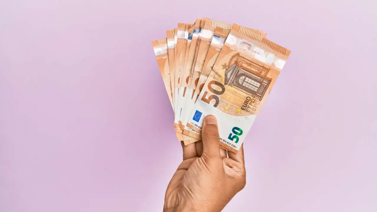 Mano che tiene banconote da 50 euro, pronte per quando si paga l'INPS.