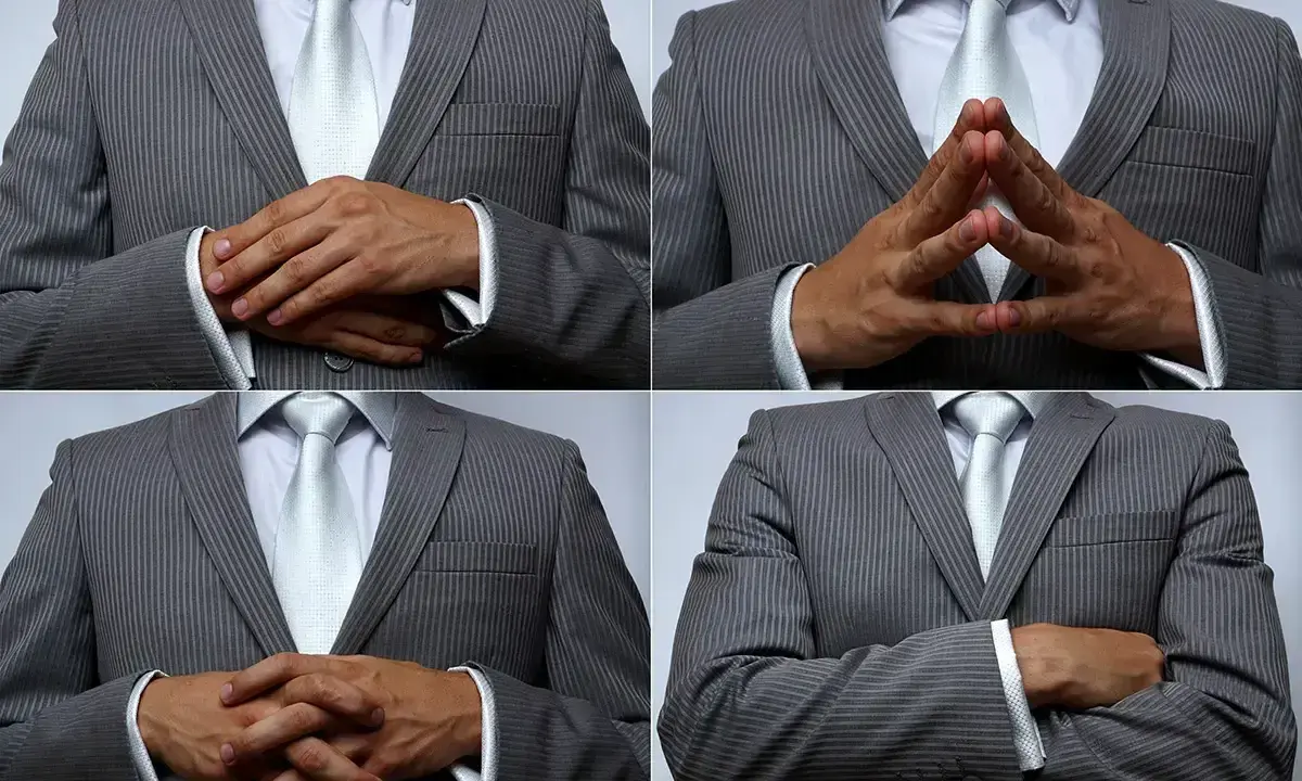 Uomo in abito grigio a righe, con cravatta chiara, che mostra diverse posizioni delle mani: incrociate, a diamante, e braccia conserte. Un modo per presentare con le mani.