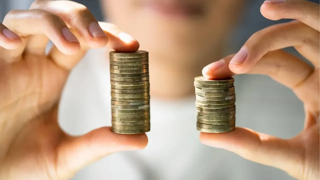 Due pile di monete, una più alta dell'altra, simboleggiano la differenza tra stipendi. Il **stipendio medio Lussemburgo** potrebbe essere rappresentato dalla pila più alta.