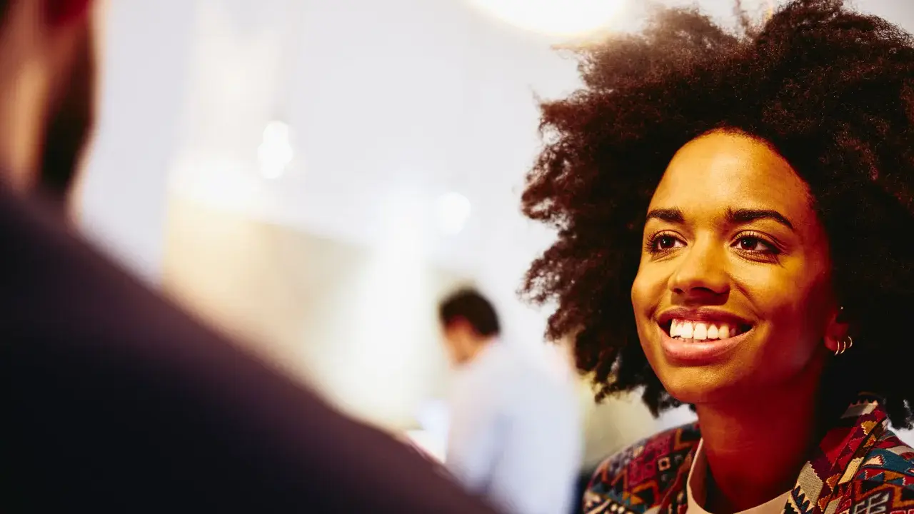 Donna sorridente in primo piano, discute idee per capire che lavoro fare a 40 anni senza esperienza.
