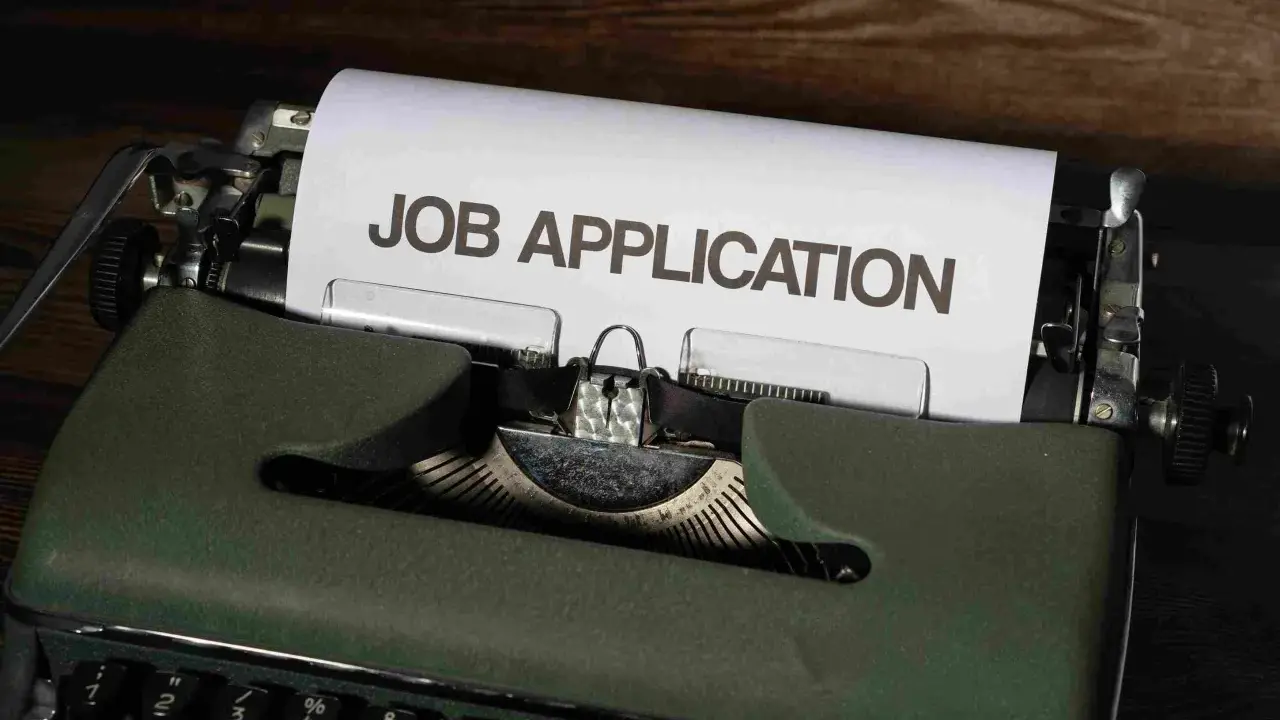 Macchina da scrivere verde con foglio "JOB APPLICATION". Una guida per chi vuole capire come trovare lavoro senza esperienza.