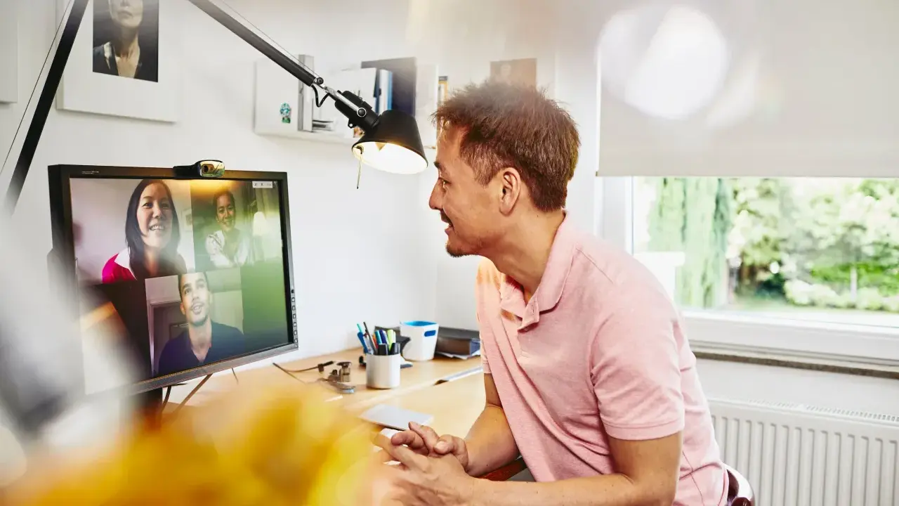 Uomo in videochiamata con colleghi, un esempio di lavoro da casa.