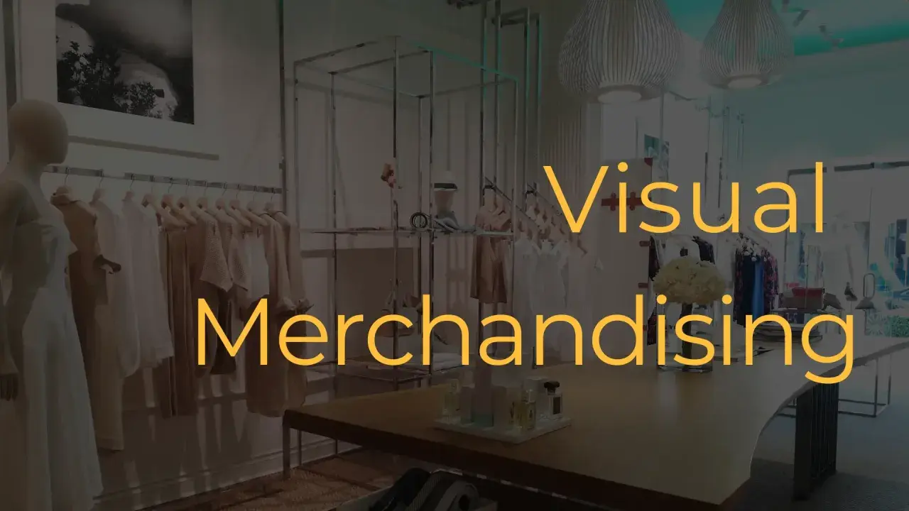Interno di un negozio di abbigliamento con manichini e abiti in esposizione. Il testo "Visual Merchandising" è sovrapposto.