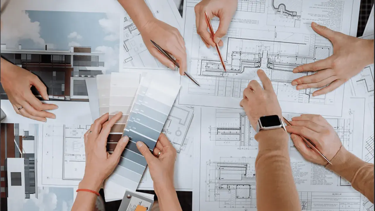 Mani che consultano progetti e campioni di colore, discutendo quanto guadagna un interior designer.