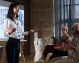 Giovane donna spiega come fare un discorso in pubblico, con un pubblico attento che applaude.