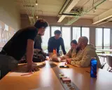 Un gruppo di giovani collabora attorno a un tavolo, un vero team di creator digitale che discute idee davanti a un laptop.