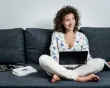 Donna con laptop e libri sul divano, esplora quali lavori si possono fare da casa.