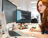 Donna con capelli rossi lavora al computer, analizzando codice. Un ingegnere gestionale cosa fa? Ottimizza processi e sistemi, proprio come lei con i dati.
