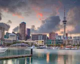 Skyline di Auckland al tramonto, con la Sky Tower e yacht ormeggiati. Un sogno per chi vuole lavorare in Nuova Zelanda.
