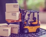 Carrellino elevatore giallo solleva scatole fragili su un pallet, mentre altre scatole attendono su una tastiera. Il buyer cosa fa? Organizza la spedizione.