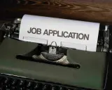 Macchina da scrivere verde con foglio "JOB APPLICATION". Una guida per chi vuole capire come trovare lavoro senza esperienza.