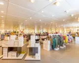 Interno di un negozio di abbigliamento con scaffali pieni di scarpe e vestiti. Un banconista cosa fa? Probabilmente sistema la merce per renderla accattivante.