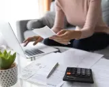 Persona analizza documenti con laptop e calcolatrice, cercando di capire quante ore di permesso si maturano al mese.