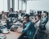 Ufficio moderno con persone al lavoro. Si discute di ccnl grafici editoriali livelli e mansioni, tra scrivanie e computer.