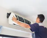 Un frigorista installa un condizionatore d'aria.