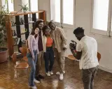 Gruppo di amici sorridenti durante un corso ufficio stampa, uno di loro scatta una foto con il cellulare.