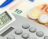 Calcolatrice con display "13.00", banconote da 10 euro e monete. Un promemoria visivo di quando viene pagata la 13esima.