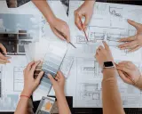 Mani che consultano progetti e campioni di colore, discutendo quanto guadagna un interior designer.