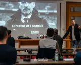 Un relatore parla a un pubblico interessato, con una proiezione che mostra "Director of Football". Un corso per chi vuole lavorare nel calcio.