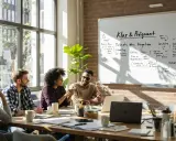 Un gruppo di persone discute idee davanti a una lavagna. La lavagna è piena di appunti e disegni, mostrando come può essere la voce di un'idea.
