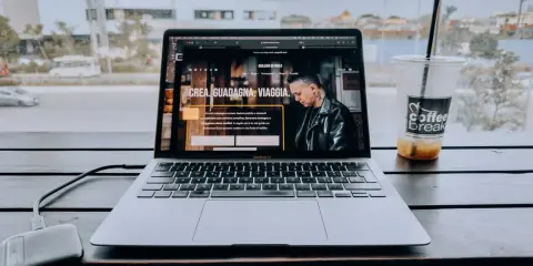 Un laptop aperto su un sito web che spiega cosa fa un content creator, con una bevanda accanto.