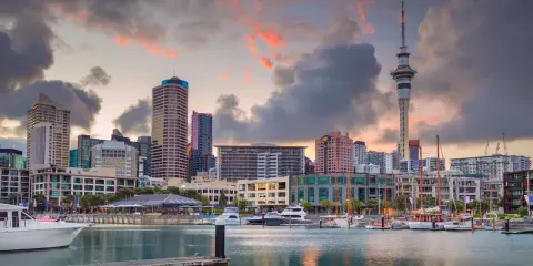 Skyline di Auckland al tramonto, con la Sky Tower e yacht ormeggiati. Un sogno per chi vuole lavorare in Nuova Zelanda.