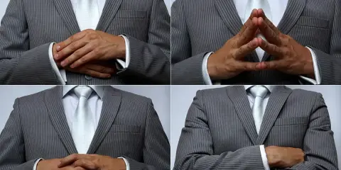 Uomo in abito grigio a righe, con cravatta chiara, che mostra diverse posizioni delle mani: incrociate, a diamante, e braccia conserte. Un modo per presentare con le mani.