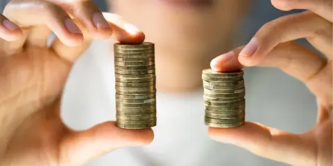 Due pile di monete, una più alta dell'altra, simboleggiano la differenza tra stipendi. Il **stipendio medio Lussemburgo** potrebbe essere rappresentato dalla pila più alta.