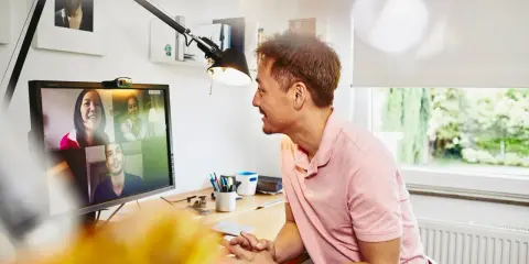 Uomo in videochiamata con colleghi, un esempio di lavoro da casa.