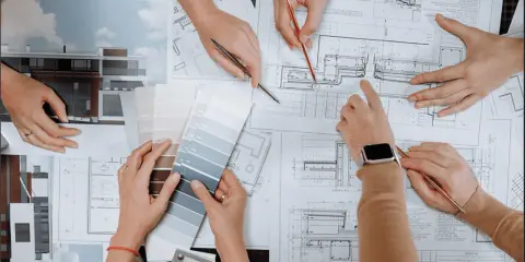 Mani che consultano progetti e campioni di colore, discutendo quanto guadagna un interior designer.
