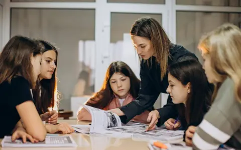 Una pedagogista guida un gruppo di ragazze nello studio, mostrando loro come affrontare un libro.