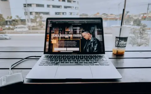 Un laptop aperto su un sito web che spiega cosa fa un content creator, con una bevanda accanto.
