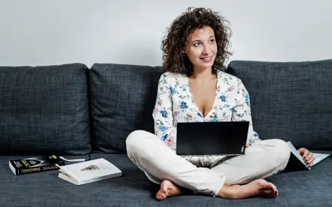 Donna con laptop e libri sul divano, esplora quali lavori si possono fare da casa.