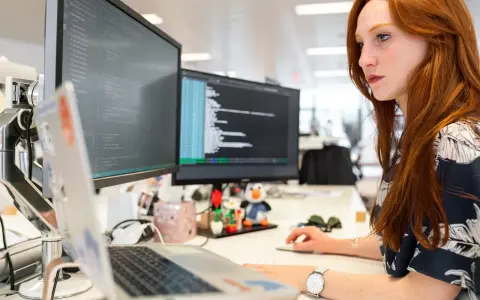 Donna con capelli rossi lavora al computer, analizzando codice. Un ingegnere gestionale cosa fa? Ottimizza processi e sistemi, proprio come lei con i dati.