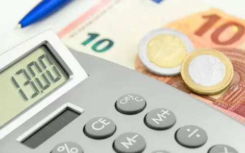 Calcolatrice con display "13.00", banconote da 10 euro e monete. Un promemoria visivo di quando viene pagata la 13esima.