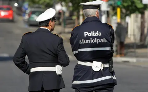 Due vigili urbani in divisa, uno con la scritta "Polizia Municipale" sulla schiena, in attesa di un equo stipendio.