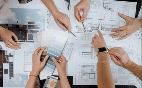 Mani che consultano progetti e campioni di colore, discutendo quanto guadagna un interior designer.