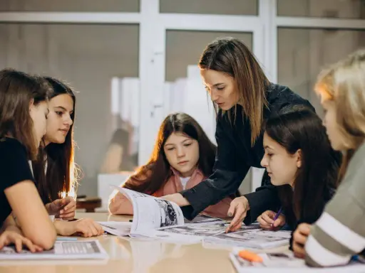 Una pedagogista guida un gruppo di ragazze nello studio, mostrando loro come affrontare un libro.