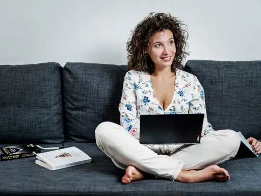 Donna con laptop e libri sul divano, esplora quali lavori si possono fare da casa.