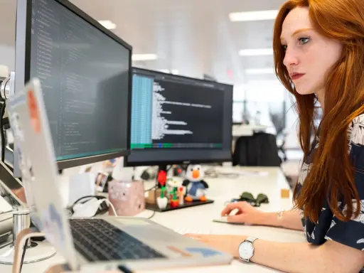 Donna con capelli rossi lavora al computer, analizzando codice. Un ingegnere gestionale cosa fa? Ottimizza processi e sistemi, proprio come lei con i dati.