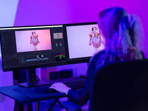 Ragazza studia effetti speciali per video, con monitor che mostra timeline e video. Corsi After Effects per creativi.