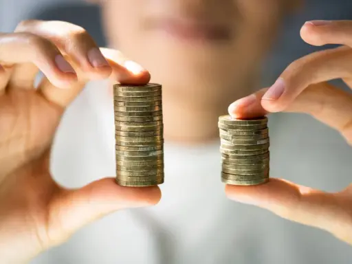 Due pile di monete, una più alta dell'altra, simboleggiano la differenza tra stipendi. Il **stipendio medio Lussemburgo** potrebbe essere rappresentato dalla pila più alta.