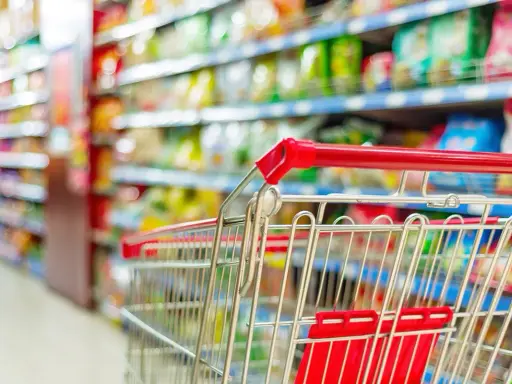 Carrello della spesa in un corridoio pieno di prodotti colorati. La GDO, o Grande Distribuzione Organizzata, è questo: un mondo di scelta.