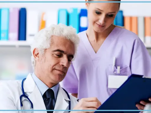Medico anziano e giovane assistente studiano insieme un referto. Un'immagine che evoca il **corso assistente studio medico**.