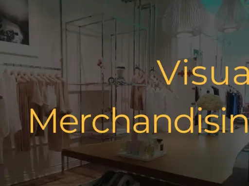 Interno di un negozio di abbigliamento con manichini e abiti in esposizione. Il testo "Visual Merchandising" è sovrapposto.