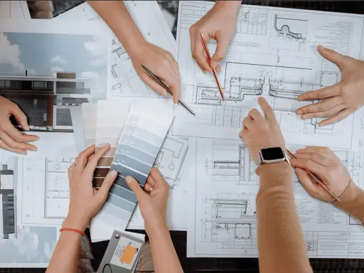 Mani che consultano progetti e campioni di colore, discutendo quanto guadagna un interior designer.